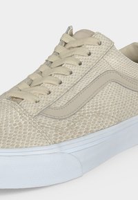Baskets beiges avec motif peau de serpent texturé, lacets crème, bande latérale signature et semelle en caoutchouc blanche.