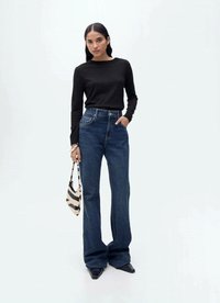 Black long-sleeve top, high-waisted blue denim flared jeans, and a striped small handbag. Model wears pointed black shoes.