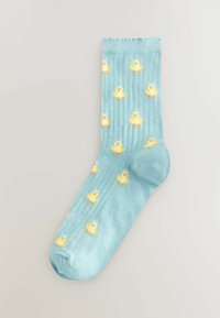 Chaussette en coton bleu clair présentant un motif répété de canetons jaunes avec des pattes orange, texture côtelée en haut et finition lisse.