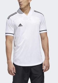 Hvid fodboldtrøje med V-hals, korte ærmer med sorte detaljer og Adidas-logoet på venstre bryst. Glat, letvægtsmateriale.