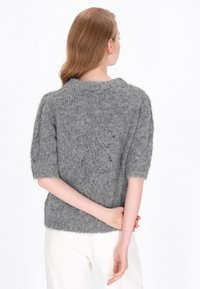 Szary, dzianinowy sweter z krótkimi rękawami, charakteryzujący się miękką, puszystą teksturą i okrągłym dekoltem, noszony z białymi spodniami.