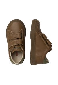 Zapatos de cuero marrón con cintas de velcro, punta redondeada y suela de goma texturizada. Presentan un acento verde en el talón y detalles de costura.