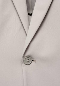 Light grey blazer featuring a tailored design, smooth texture, notched lapels, and a single grey button closure.