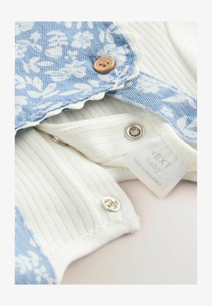 Denim bodysuit with a blue floral pattern, white ribbed fabric, scalloped edges, and snap fasteners. Includes a tag labeled "NEXT baby."