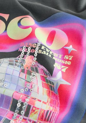 Czarna tkanina z kolorową grafiką kuli dyskotekowej. Podkreślona cekinami i wyrazistym tekstem. Widoczne jasne odcienie różowego, fioletowego oraz srebrne gwiazdy.