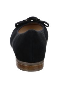 Ballet flat in suede nero con punta arrotondata, grande fiocco singolo decorativo sul tallone e suola bassa in marrone testurizzato.