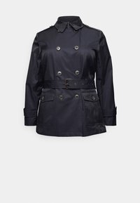 Trench coat azul marino, de doble botonadura, con cintura ceñida por un cinturón, mangas largas, hombreras y dos bolsillos frontales. Tejido suave y texturizado.