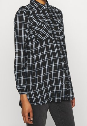 Camicia a quadri nera e blu con maniche lunghe, chiusura frontale con bottoni, due tasche sul petto, orlo arrotondato e tessuto morbido.