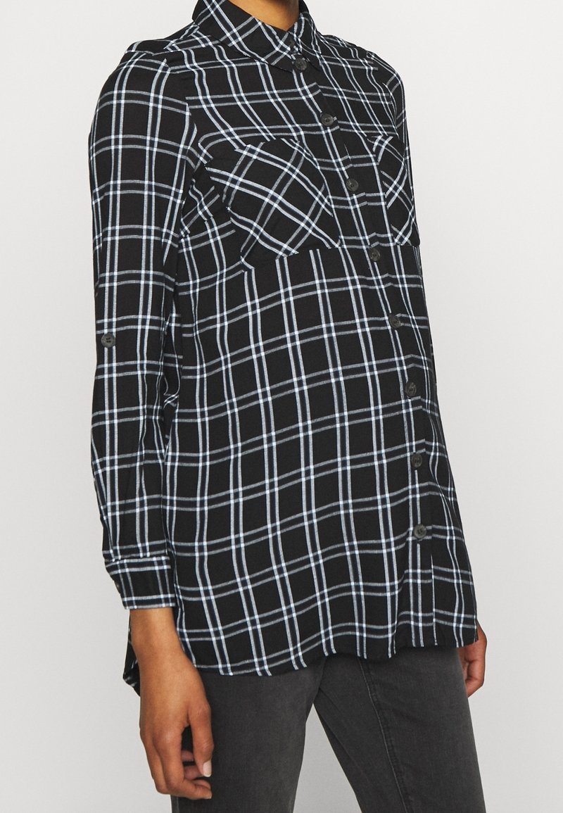 Svart och blå rutig skjorta med långa ärmar, knappstängning fram, två bröstfickor, rundad nederkant och mjuk tygkvalitet.