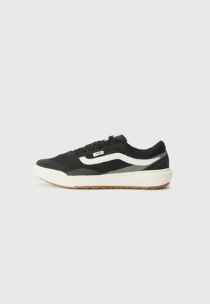 Black athletic shoe featuring a textured upper, white stripe, and a gum rubber outsole. Includes laces and a cushioned midsole for support.