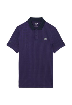 Polo shirt viola con un motivo a griglia testurizzato, maniche corte e colletto blu navy. Presenta un logo Lacoste verde sul petto.