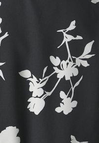 Czarna tkanina o gładkiej fakturze z dużymi białymi kwiatowymi nadrukami, przedstawiającymi różne kształty kwiatów oraz zielone liście.