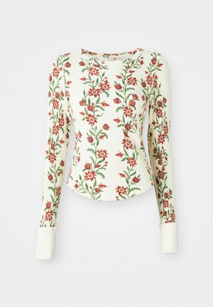 Long-sleeve shirt made of textured fabric, featuring a white base with red floral patterns and green leaves; includes white cuffs.