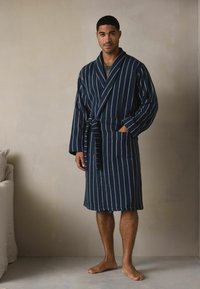 Tumši zili svītrots ģērbtuvju apvalks ar jostu, garām piedurknēm, divām priekšējām kabatām un mīkstu tekstūru. Viegls audums, ceļa garuma dizains.