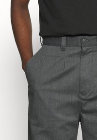 Grijze broeken met een gestructureerde afwerking, voorzien van een platte voorkant, zijzakken, riemlussen en een metalen knoop in de taille.