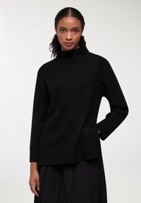 Czarny sweter typu golf w miękkim, teksturowanym splotcie. Posiada luźny krój, prążkowane mankiety oraz boczne rozcięcia dla większej wygody i stylu.