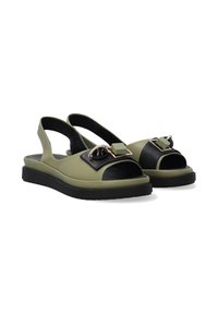 Grüne und schwarze Slingback-Sandalen mit flacher Sohle, offener Zehenpartie und dekorativen Hardware-Akzenten im geometrischen Design.