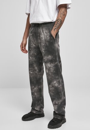 Graue Batik-Hosen mit lockerer Passform, elastischem Bund und zwei seitlichen Taschen, kombiniert mit schwarzen Sneakers.