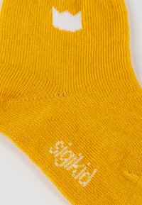 Gelber gestrickter Socken mit einem weißen Kronenmuster oben und weißem Text "sighd." Weiche Textur mit elastischem Bündchen für den Sitz.
