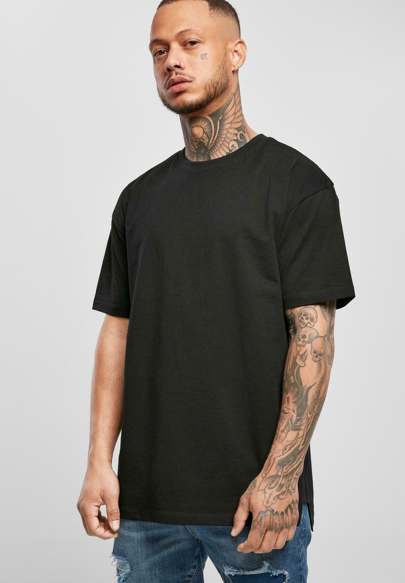 Svart kortermet t-skjorte laget av bomull, med rund hals og en avslappet passform, iført med slitte blå jeans.