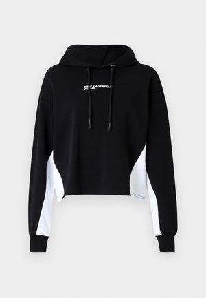 Musta cropped huppari valkoisilla sivupaneeleilla, nauhakuuluvalla hupulla ja etupainatuksella. Valmistettu pehmeästä kankaasta; siinä on pitkät hihat ja ribbitaskut.