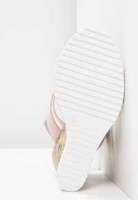 Lichtroze sandalen met een geborstrekte stof bovenkant, een natuurlijke kurken zool, en een witgestreepte rubberen zool, bekeken vanaf de onderkant.