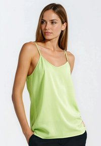Limonkowo-zielona koszulka na cienkich ramiączkach, z dekoltem w serek i gładkiej, lekkiej tkaniny; lekko luźny krój z swobodnym układem.