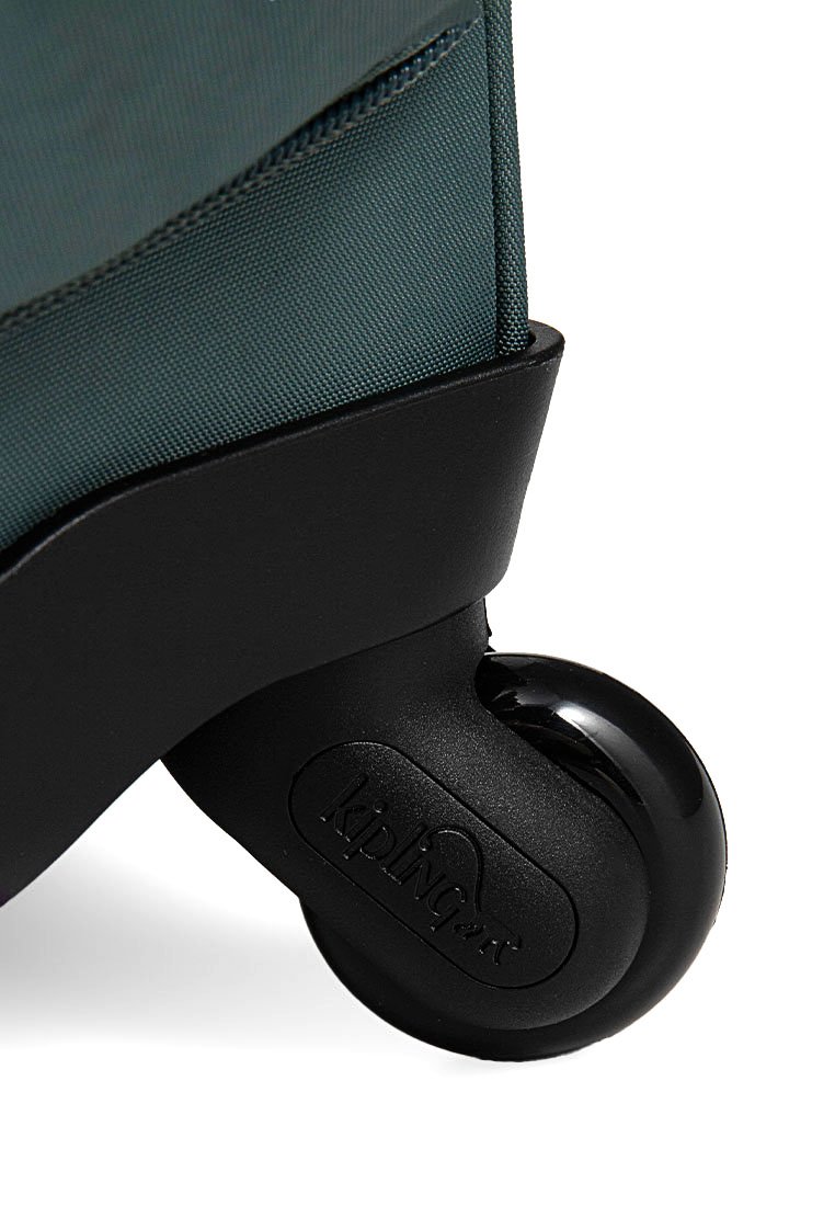 Gros plan sur une roue en plastique noir fixée à un coin de valise en tissu bleu foncé, avec le logo Kipling sur le boîtier de la roue.