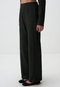 Brede, donkergrijze broek van gestructureerde stof met een ruitpatroon; heeft een hoge taille en een soepele, elastische tailleband.