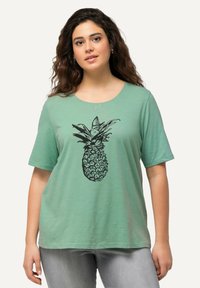 Mintgrünes T-Shirt mit kurzen Ärmeln, das auf der Vorderseite mit einem schwarzen Ananas-Graphic-Design ausgestattet ist, aus weichem, leichtem Stoff hergestellt.