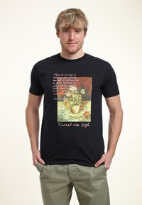 Camiseta de algodón negra con un estampado de un bodegón floral, atribuido a Vincent van Gogh, con un texto en una fuente clara.