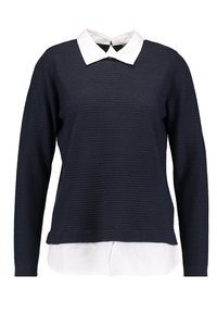 Marinblå strukturstickad tröja med långa ärmar och en vit kragskjorta som syns underifrån, med en avslappnad passform och ribbade detaljer.