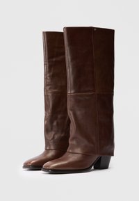 Braune Leder-Stiefel bis zum Knie mit glatter Textur, quadratischem Zehendesign und Blockabsatz. Mit Nahtdetails an der Wade.