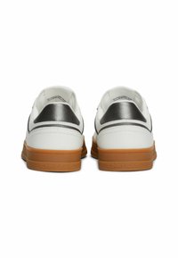 Sneakers bianchi con un accento argento sul tallone e una suola in gomma beige. Texture opaca con finitura liscia. "TOMMY JEANS" impresso sulla suola.