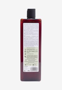 Mörk bärnstenfärgad plastflaska med ett svart flip-top-lock. Vit och grön text på baksidan beskriver ingredienser och användningsanvisningar.