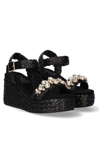 Sandalias cuña negras con textura trenzada, adornadas con acentos de piedras preciosas transparentes en las correas, con hebilla ajustable en el tobillo.