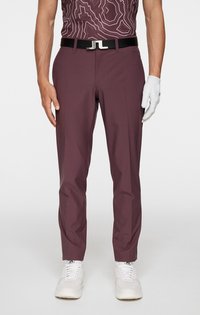 Bordowe spodnie golfowe o dopasowanym kroju, zestawione z czarnym paskiem z metalową klamrą w kolorze srebrnym. Noszone z białą rękawiczką i białymi trampkami.