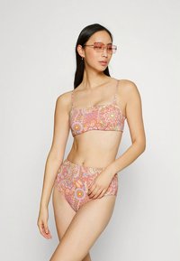 Kaksiosainen bikini monivärisellä kukkaprintillä. Yläosa on bandeau-tyyliä, ja vyötäröä korostavat alaosa on samanlaista kuosia.