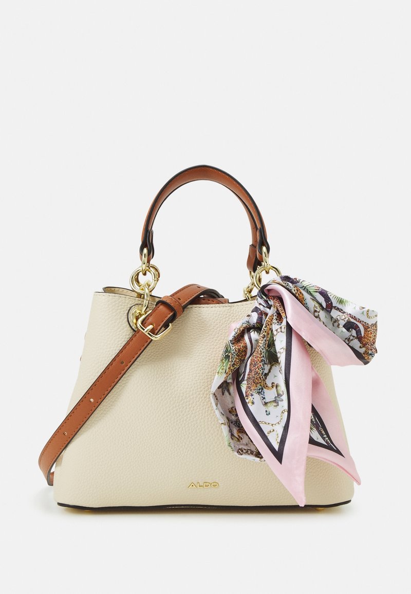 Sac à main texturé crème avec poignées marron, bandoulière ajustable, accessoires dorés et foulard en soie rose à motifs noué à une poignée.