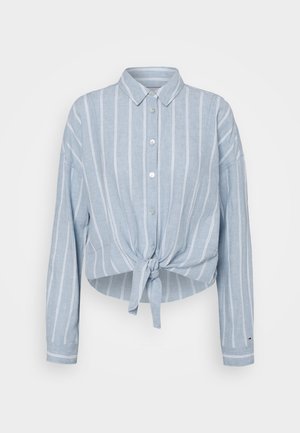 Camisa de manga larga azul claro con rayas verticales blancas, cierre de botones en el frente, cuello y detalle de nudo atado en la cintura.