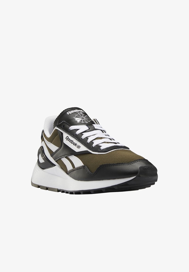 Teniska Reebok v olivově zelené a černé textilii s bílými detaily, výrazným logem, členitou podrážkou a klasickým atletickým designem.