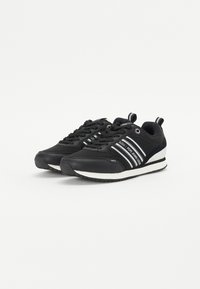 Sneakers neri con finitura liscia, caratterizzati da righe bianche, punta arrotondata e suola testurizzata. Include elementi di branding e accenti circolari.