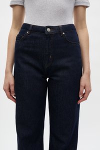 Dunkelblaue Jeans aus Denim mit high waist, mit orangefarbenen Nähten, frontalen Taschen und einem silbernen Knopfverschluss. Glatte Textur, gerader Schnitt.