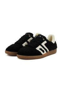 Sneakers in bianco e nero con texture, suole in gomma color nocciola, lacci neri e foderato interno bianco, inclinati a sinistra su uno sfondo bianco.