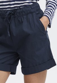 Marina bomullsshorts med elastisk midjeband och dragsnöre. Har sidofickor och uppvikta muddar som ger en avslappnad passform.