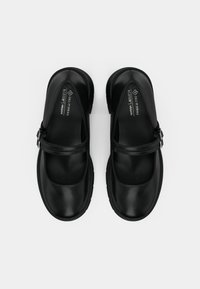 Ζευγάρι μαύρα vegan παπούτσια Mary Jane με λουριά και πόρπες, στρογγυλεμένες μύτες και επενδεδυμένες σόλες, πάνω σε λευκό φόντο.