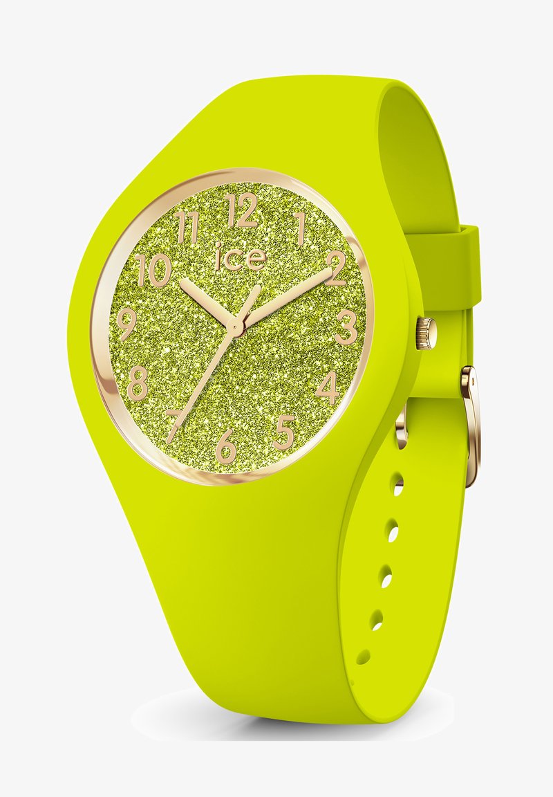 Neon dzeltena silikona pulksteņa ar spīdīgu zaļu seju, zelta stundu rādītājiem un zelta akcentiem. Tam ir apaļa korpusa forma un regulējams siksna.