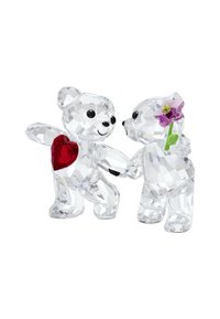 Två kristallbjörnfigurer som håller händer, en med ett rött hjärta på bröstet och den andra som håller en rosa blomma, glänsande och fasetterade detaljer.
