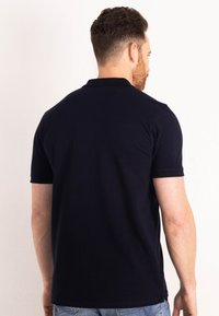 Námořnická modrá polo tričko s krátkými rukávy, vyrobené z hladké látky, s klasickým límečkem a rovnými lemy. Viditelné švy na švech.