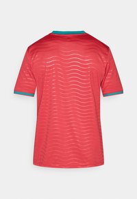 Κόκκινη φανέλα με μοτίβο κυμάτων, με λαιμόκοψη crew neck και τυρκουάζ λεπτομέρειες στα μανίκια. Κατασκευασμένη από ελαφρύ ύφασμα.